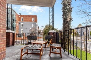 Een balkon met buitenmeubels en uitzicht op een gebouw en een boom.
