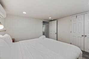 Une chambre d’hôtel avec un grand lit, une table de chevet, une armoire et une porte donnant sur une salle de bain.