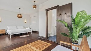 Ein modernes Schlafzimmer mit Holzboden, einem weißen Bett, einer Holzbank und einem großen Spiegel.