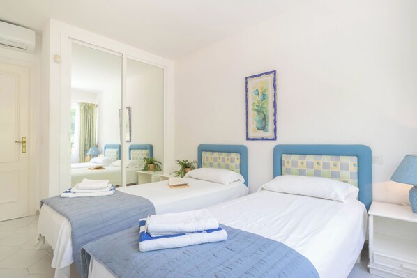 A hotel room with two beds, a large mirror, a painting, and a bedside table with a lamp. - Casa Limonero Miraflores (Mijas)