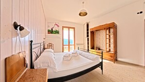 Une chambre avec un lit, une armoire en bois, une fenêtre donnant sur un beau paysage et un luminaire suspendu.