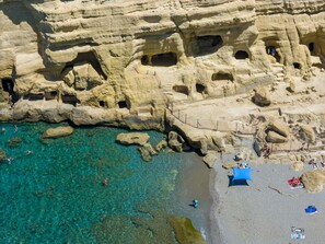 A rocky cliff with multiple caves and a clear turquoise sea. - In the center of famous Matala (Matala)
