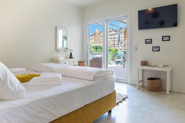 A bedroom with a bed, a white dresser, a television, and a view of the outdoors. - In the center of famous Matala (Matala)