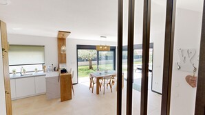 A modern kitchen with white cabinets, a wooden island, and a dining area with a table and chairs. - Villa Silvia in Mihatovici (Mihatovici)