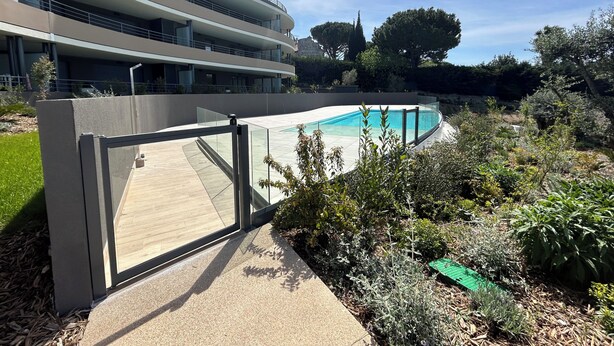 A modern building with a pool, surrounded by greenery and trees.