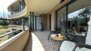 A balcony with a seating area, a table with a book and a cup, and a chair.