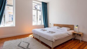 A bedroom with a bed, two bedside tables, a night lamp, and a window with curtains. - Architect Garden House (Brussels)