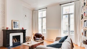 A cozy living room with a fireplace, a leather armchair, a sofa, and a bookshelf. - Architect Garden House (Brussels)
