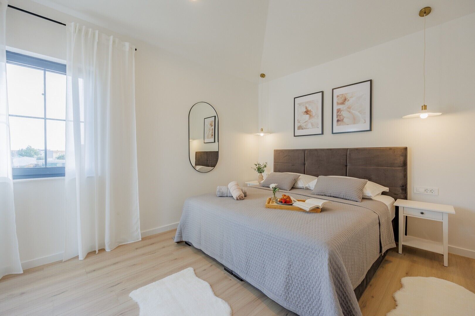 Un dormitorio moderno con una cama grande, una mesita de noche, un espejo y obras de arte en la pared.