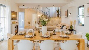 A dining area with a wooden table set for six, white chairs, and a staircase in the background. - Luxury Villa Oliva Oliana heated pool 32m2, bbq, family (Vrsi)