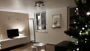 A living room with a sofa, a small table, a TV, and a Christmas tree. - Cosy and spacious village house in the historic center of Turckheim (Turckheim)