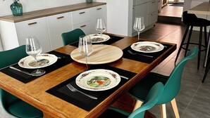 A dining area with a wooden table set for four, green chairs, and a kitchen in the background. - Cosy and spacious village house in the historic center of Turckheim (Turckheim)