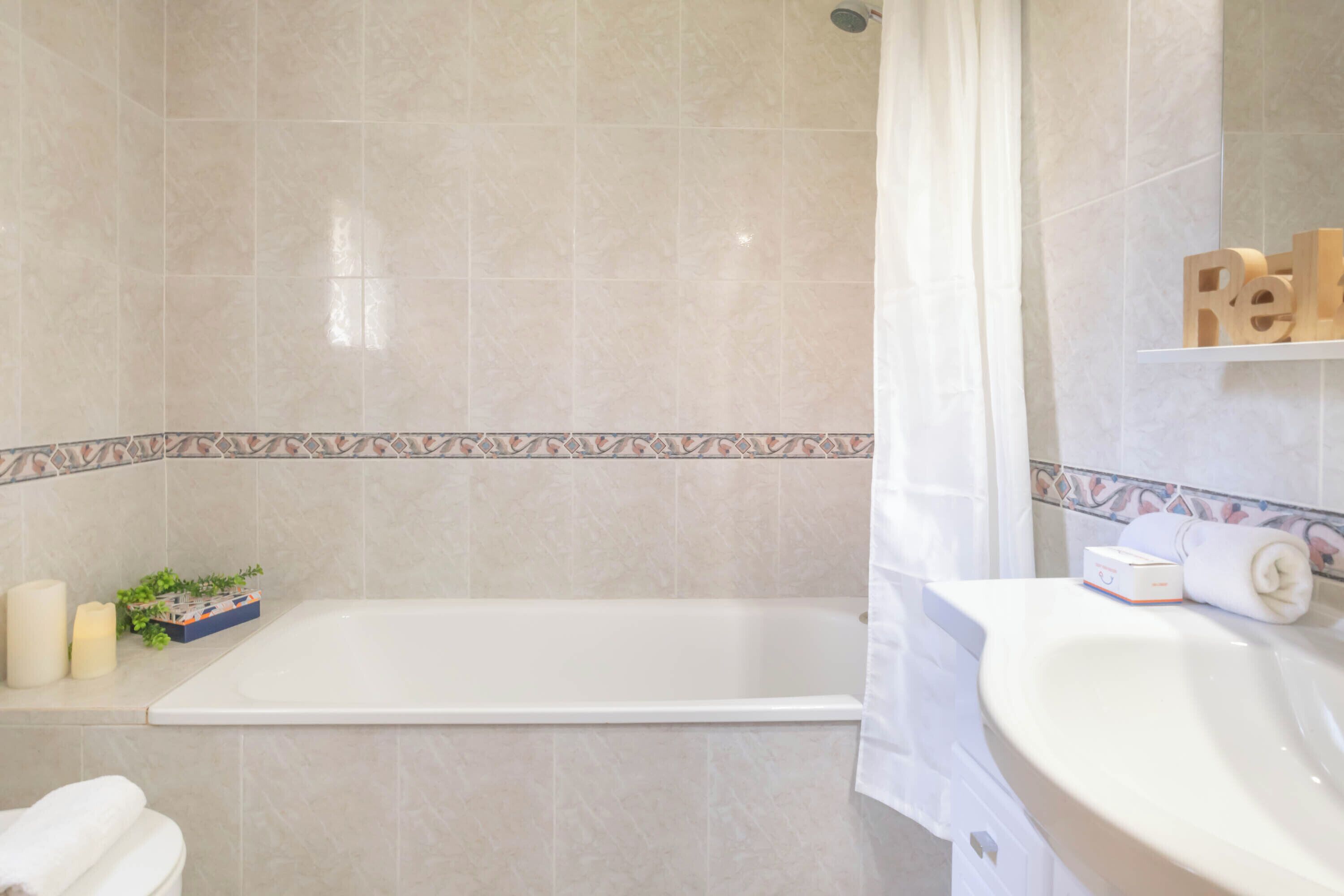 Une salle de bain avec une baignoire, un lavabo et un rideau de douche.