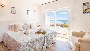 A bedroom with two beds, a view of the sea, and a balcony with outdoor furniture. - Bahia Dorada Beach (Estepona)