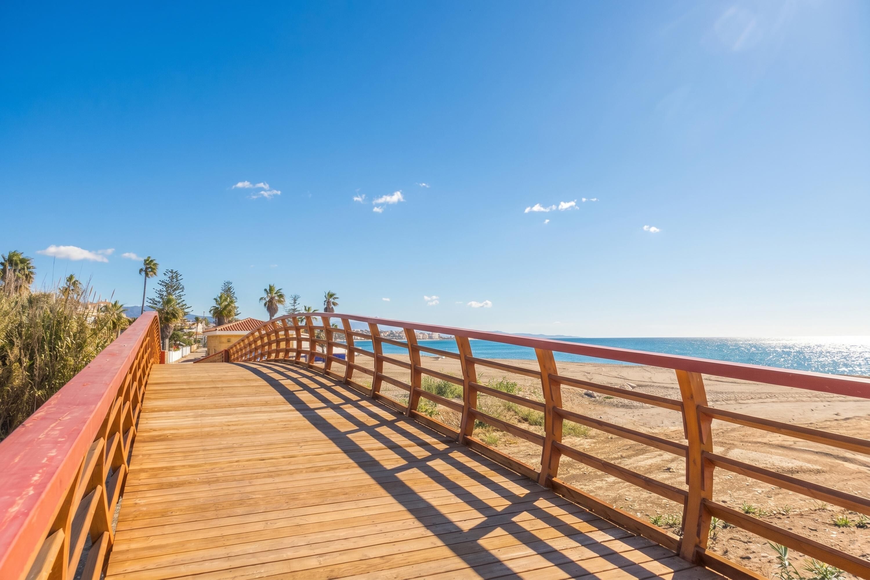 A wooden boardwalk leading to a beach with a clear sky.