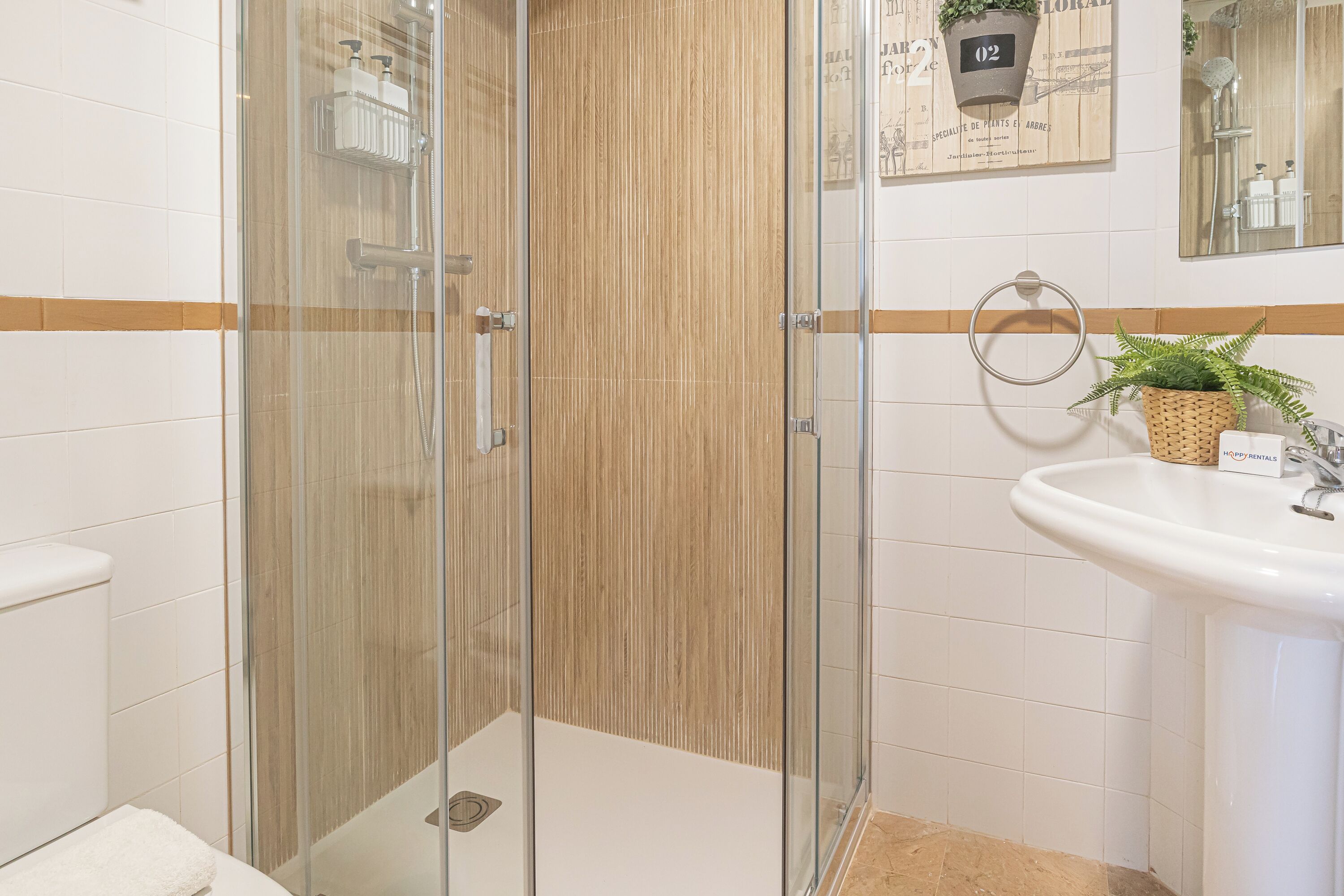 A modern bathroom with a glass shower enclosure, a white sink, and a wooden accent wall.