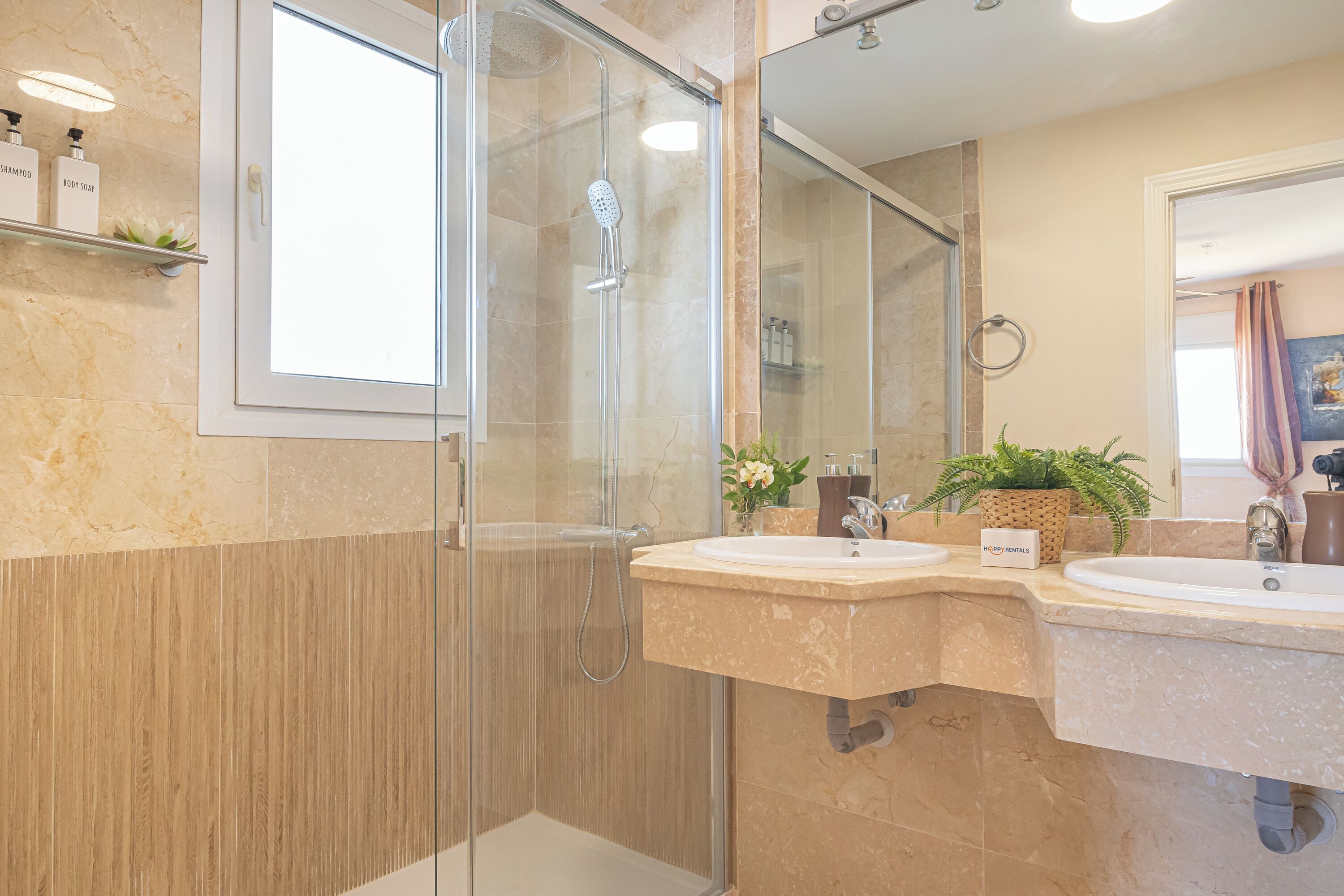 A modern bathroom with a glass-enclosed shower, two sinks, and a mirror.