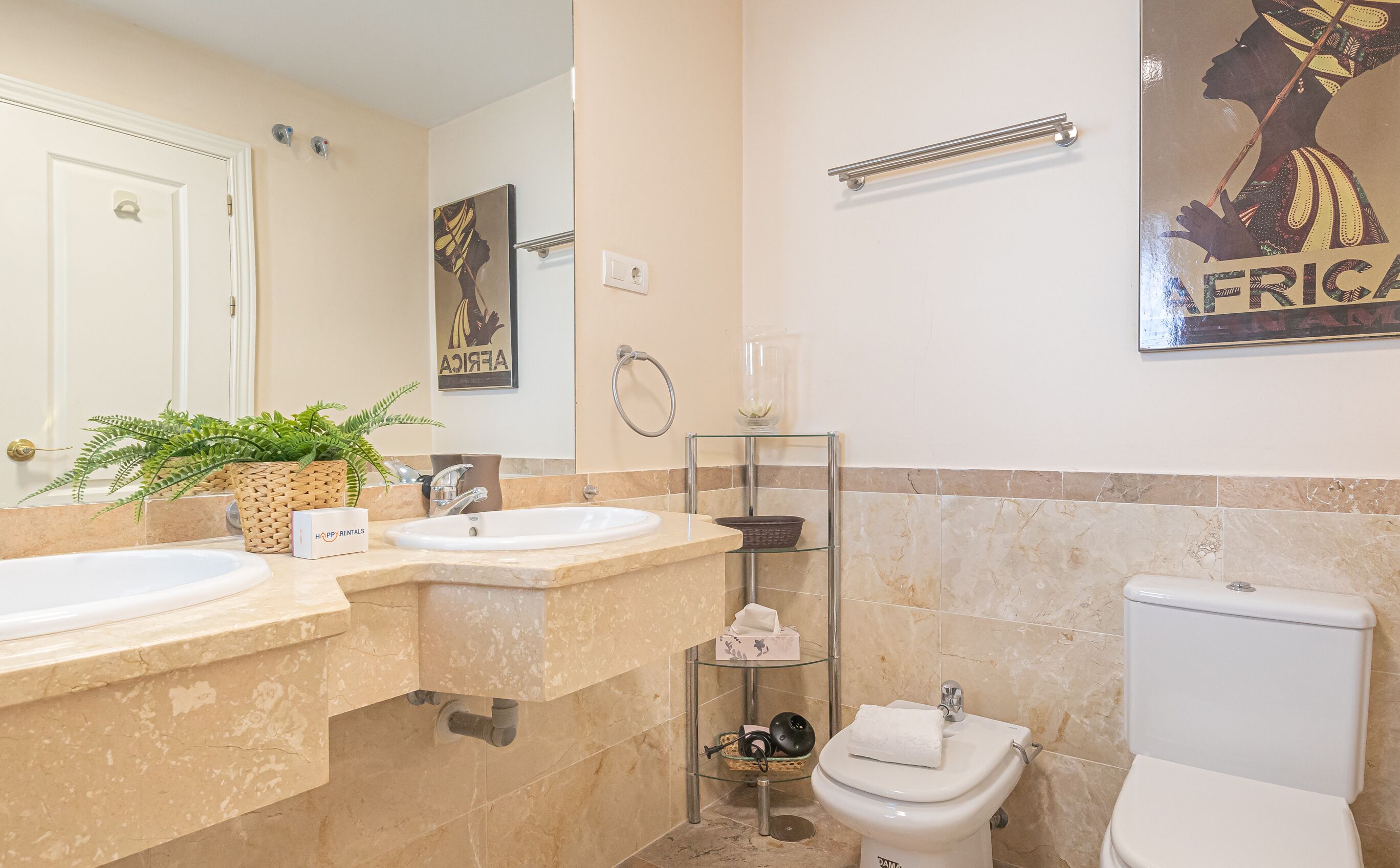 A bathroom with two sinks, a toilet, a glass shower enclosure, and a towel rack.