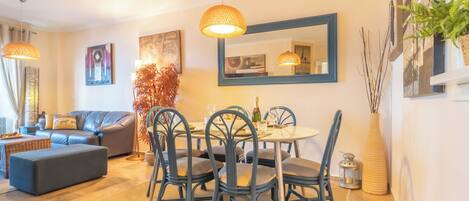 A dining area with a round table, chairs, and hanging pendant lights.