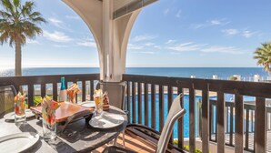 Un balcón con vista al mar, una mesa con sillas y elementos decorativos.