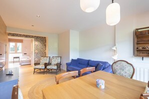 A dining area with a wooden table, chairs, and a blue sofa.
