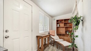 A hallway with a white door, a wooden bench, a chair, a window with blinds, and a wooden bookshelf. - Nob Hill Haven, near UNM (Albuquerque)