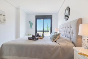Une chambre à coucher avec un grand lit, une table de chevet, une fenêtre donnant sur un beau paysage et un miroir au mur.