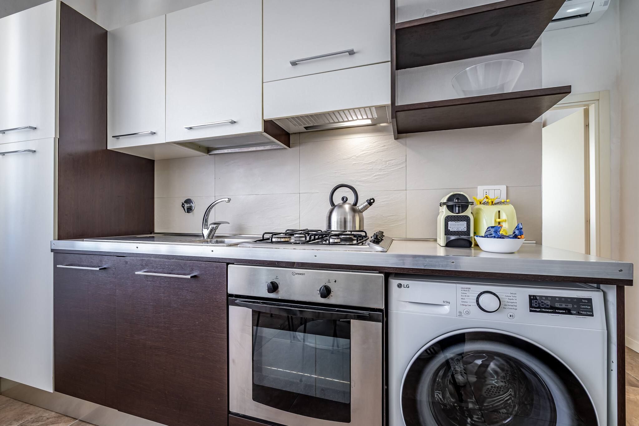 A compact kitchen with a gas stove, oven, and front-loading washing machine.