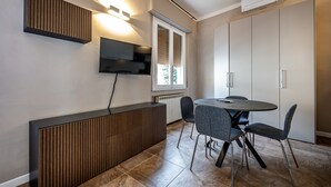 Una cocina moderna con estufa integrada, una mesa de comedor con cuatro sillas y un televisor montado en la pared.