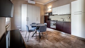Una cocina compacta con comedor, que cuenta con electrodomésticos modernos, horno integrado y una mesa con sillas.
