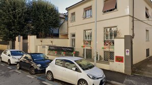 Un edificio residencial con entrada protegida por un portón, un estacionamiento con tres autos y un letrero que indica zona prohibida para estacionar.