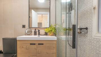 A modern bathroom with a wooden vanity, a glass shower enclosure, and a mirror above the sink.