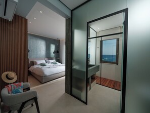Une chambre à coucher moderne avec un lit, une chaise, une coiffeuse et une vue sur la mer.