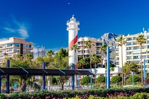A coastal hotel with a prominent lighthouse, modern buildings, and lush greenery. - Coronado Beach Marbesa (Marbella)