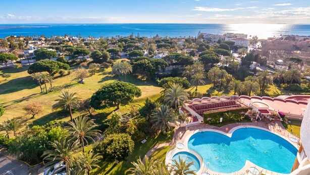Ein Resort mit Schwimmbad, üppiger Bepflanzung und Meerblick.