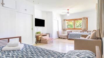 Une chambre avec deux lits, un bureau, une chaise, une télévision et une fenêtre avec des rideaux.