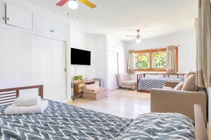 Une chambre avec deux lits, un bureau, une chaise, une télévision et une fenêtre avec des rideaux.