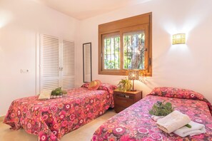 Una camera da letto con due letti, una finestra vista, un comodino e una lampada a parete.