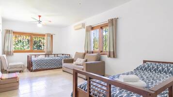 A room with a bed, a sofa, a chair, and a window with curtains.