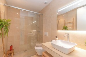 A modern bathroom with a glass shower enclosure, a white sink, and a toilet. - Casa La Cala Valvega (Mijas)