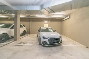 Un parking avec deux voitures blanches stationnées dans des emplacements réservés à cet effet.