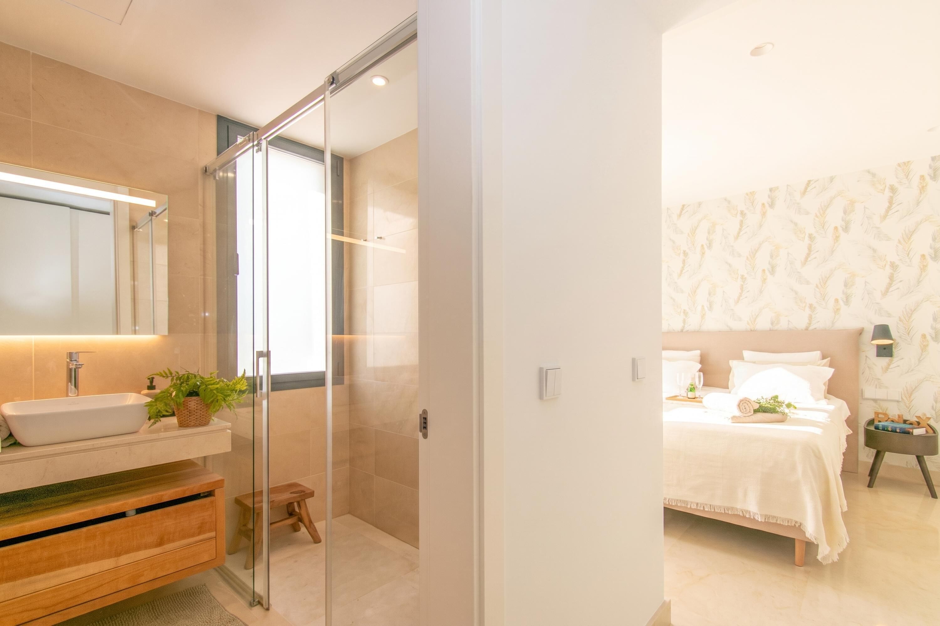 A modern bathroom with a glass shower enclosure, a white sink, and a wooden vanity.