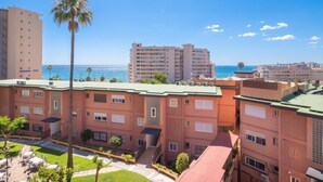 A multi-story building with balconies, a palm tree, and a view of the ocean. - Cambural Beach Apartment (Fuengirola)