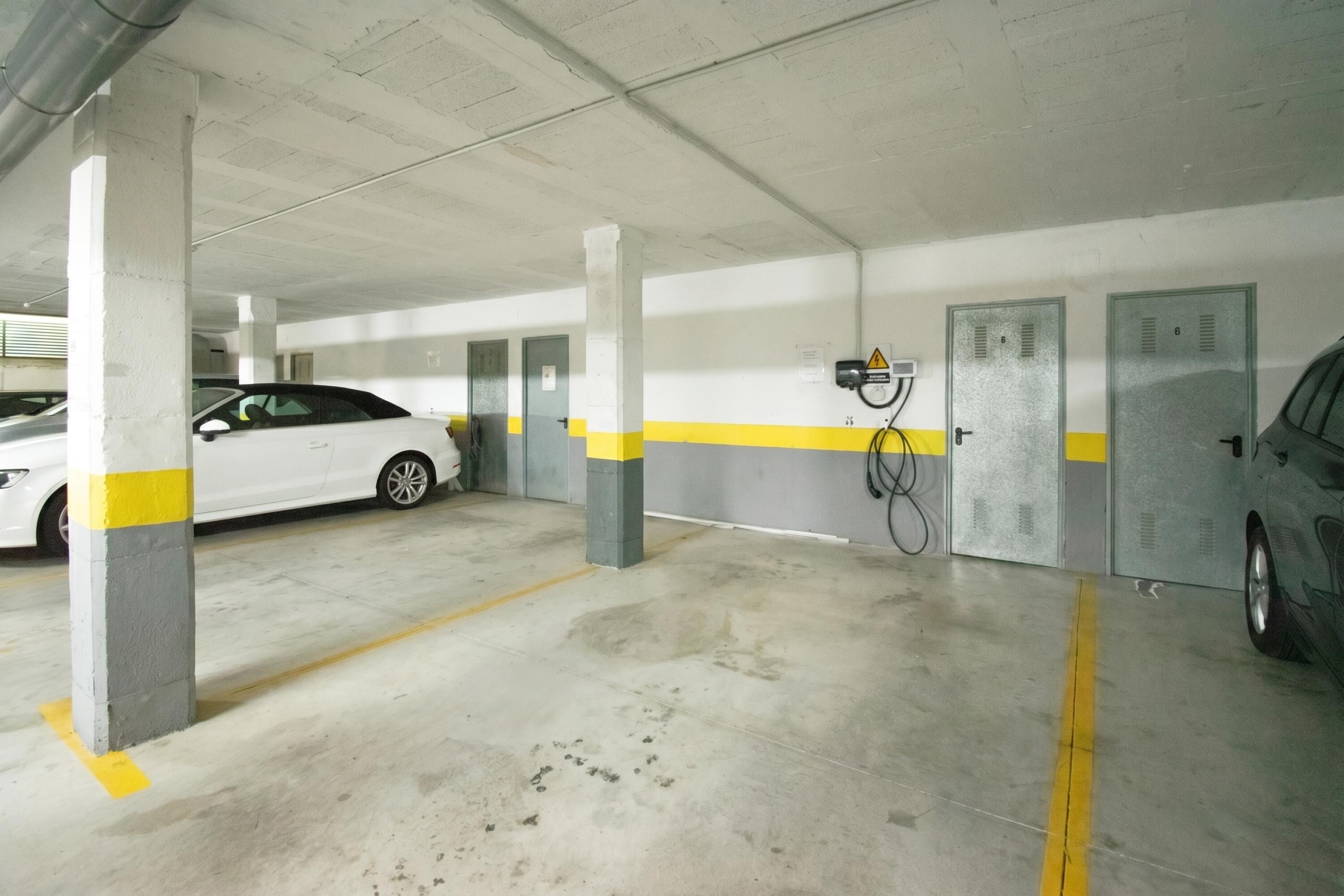 Un parking avec des piliers en béton, des lignes jaunes et des casiers métalliques.