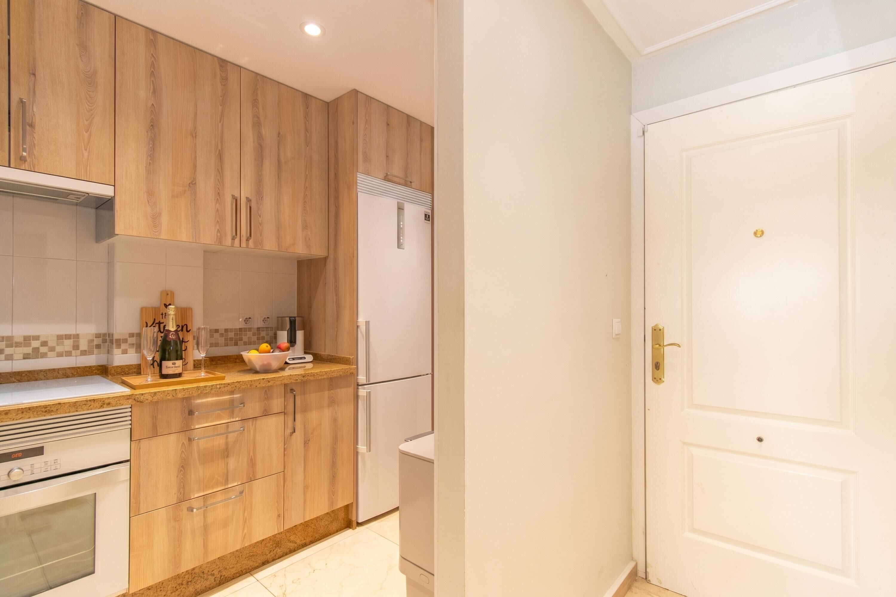 Una cocina con armarios de madera, un refrigerador blanco y un horno blanco.