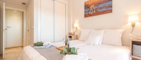 A hotel room with a bed, a painting, a nightstand, and a door.