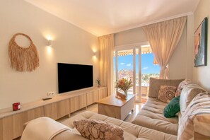 A modern living room with a flat-screen TV, a wooden console table, and a sofa with patterned cushions. - Paraiso De Riviera (Mijas)