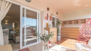 A spacious living area with a sliding glass door leading to a balcony, a white sofa, a coffee table, and a potted plant. - Paraiso De Riviera (Mijas)
