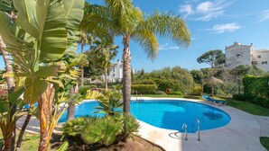 A swimming pool surrounded by lush greenery and palm trees, with a clear blue sky. - Paraiso De Riviera (Mijas)