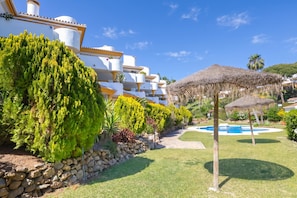 A resort with white buildings, a swimming pool, and a thatched umbrella. - Calahonda Golf (Mijas)